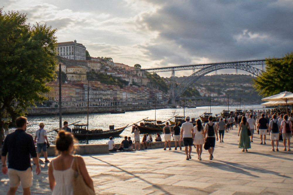 Crowds crossing a riverside square in Porto on a bright summer afternoon