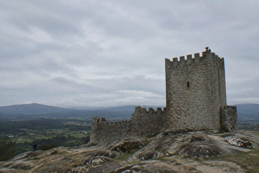 A square medieval keep standing on bare granite with open countryside behind it