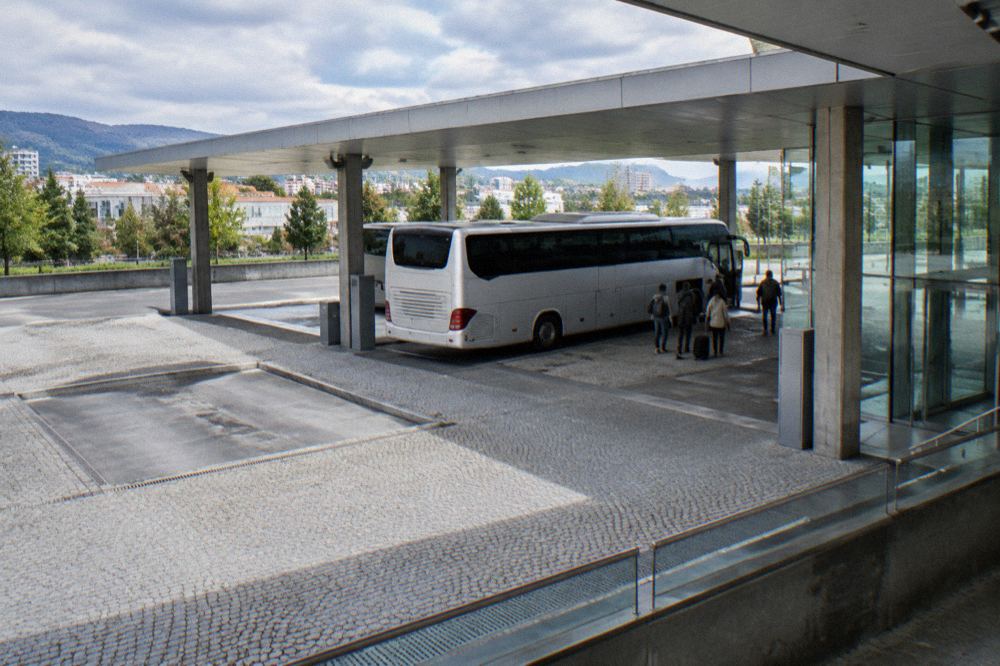 A long-distance coach parked at a modern bus station with passengers boarding