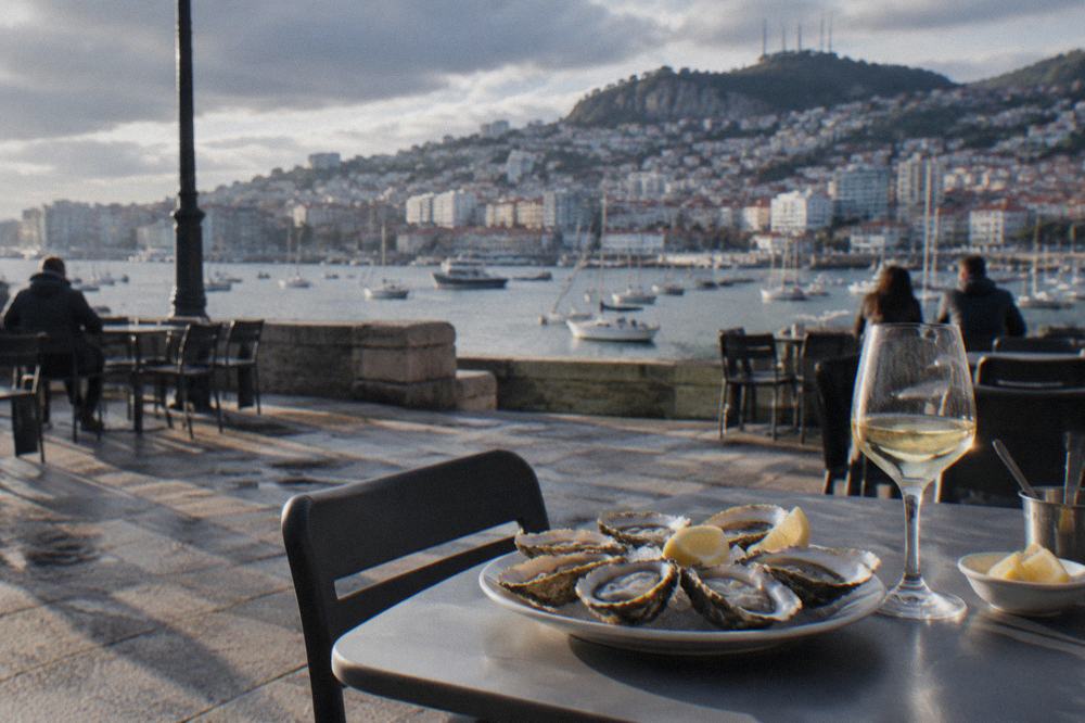 An open plate of fresh oysters on a café table in a Galician square