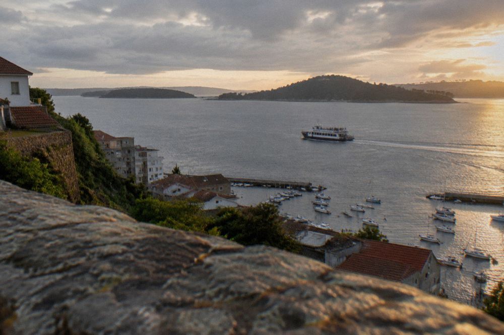 A ferry crossing open water towards green islands with passengers on deck