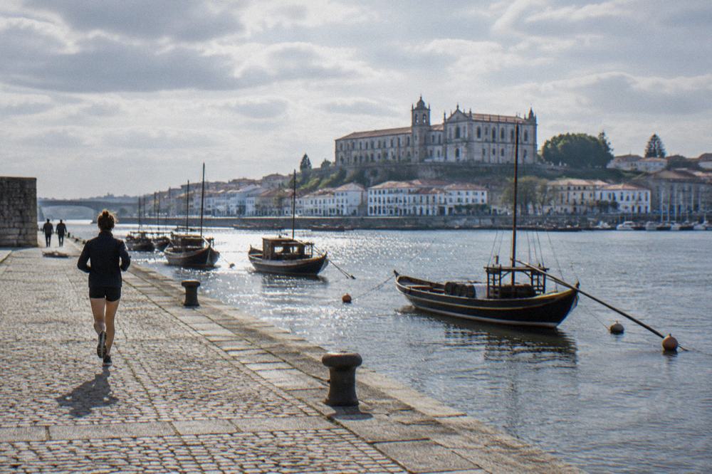 A historic convent building above a river with a town skyline behind it