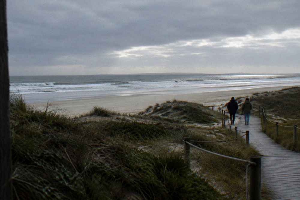 Two walkers on a coastal path between dunes and the ocean in northern Portugal