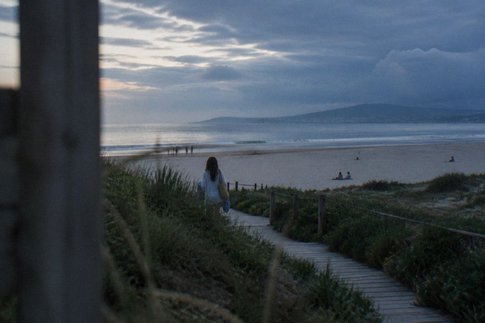A summer beach scene with calm Atlantic water and a wide empty stretch of sand
