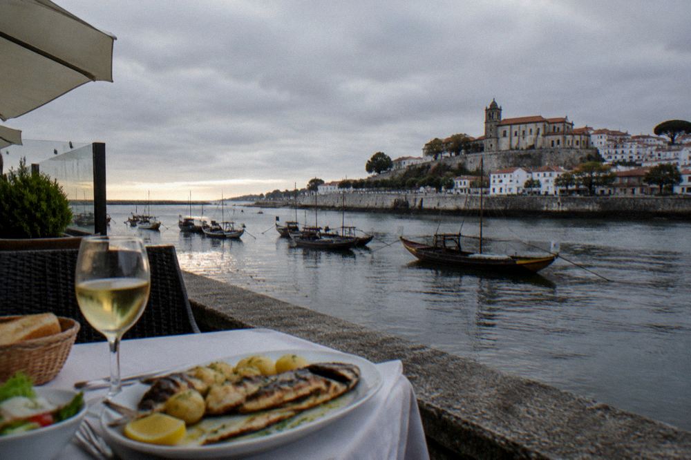 A grilled fish dinner with potatoes and wine on a restaurant table by the sea