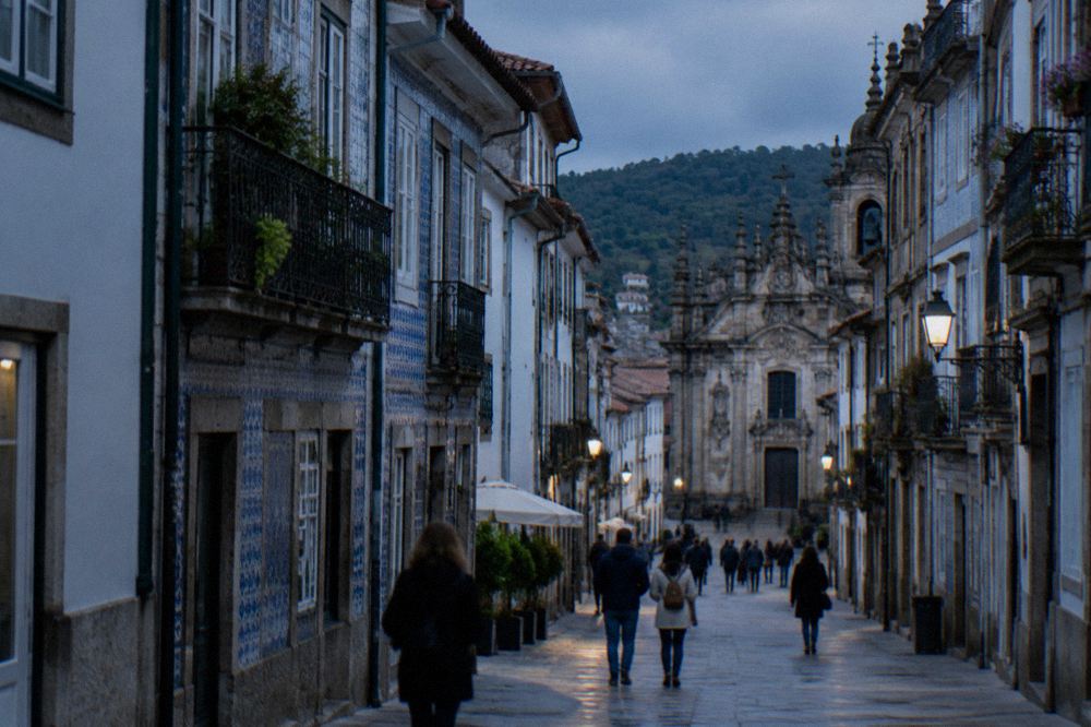Visitors walking along a sunlit street of old buildings in Braga's historic centre