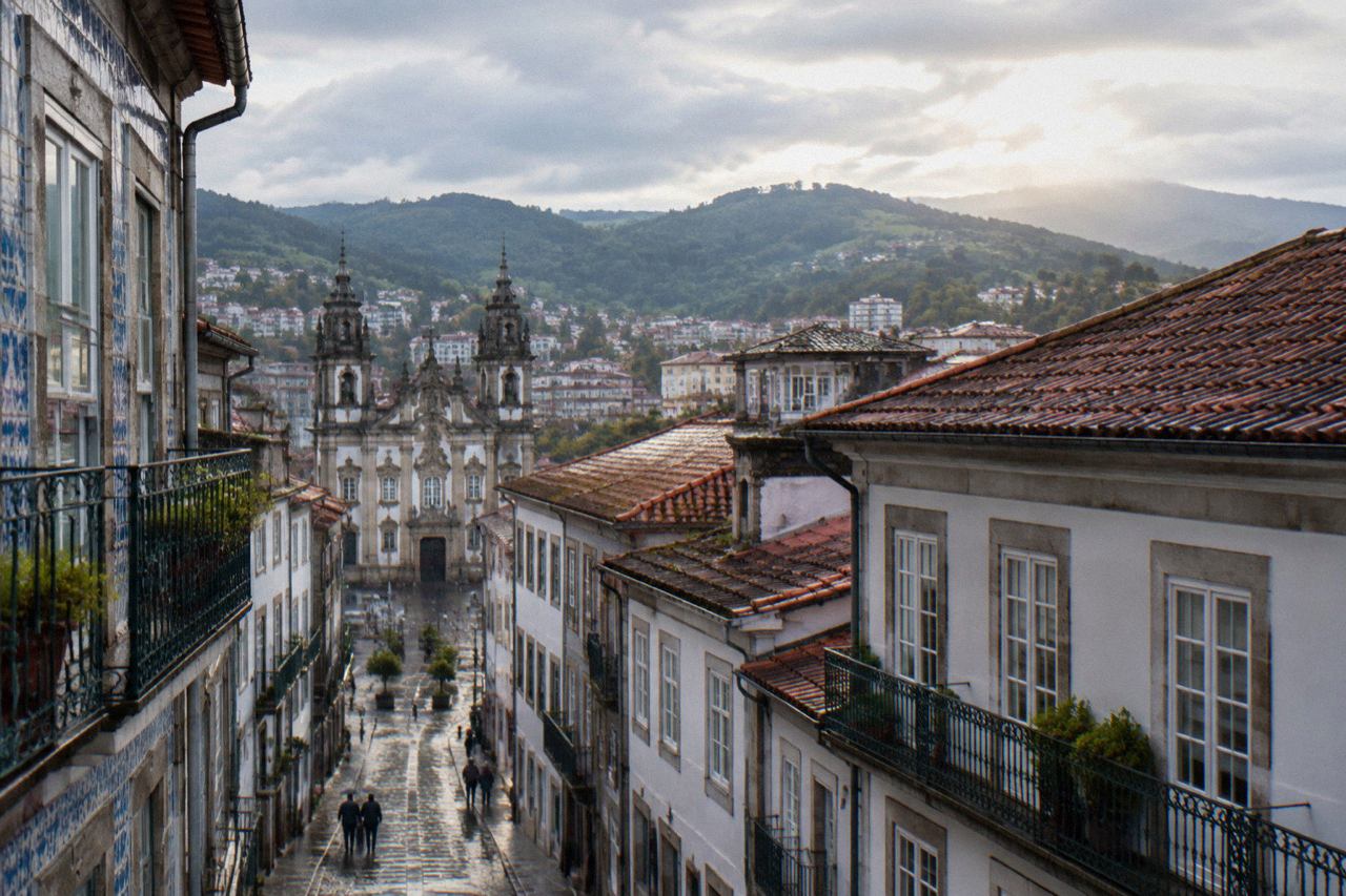 A view over the rooftops and church towers of Braga with green hills rising behind the city