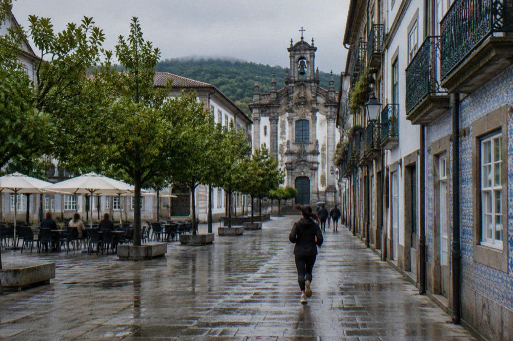 A leafy central square in Braga with outdoor cafe tables on flat stone paving