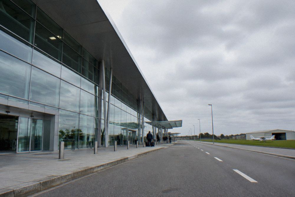A small regional aerodrome with a light aircraft parked on grass beside a low hangar