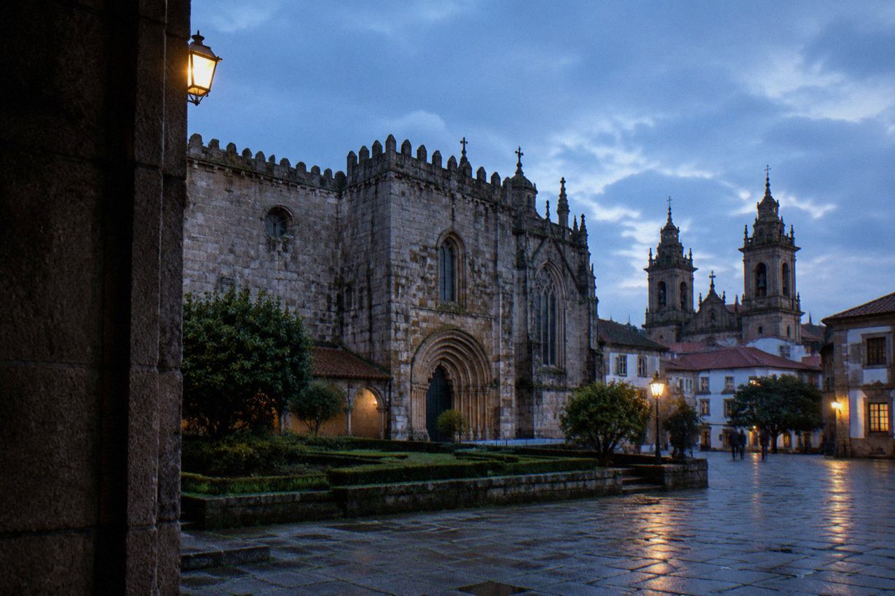 A stone square in Braga with the cathedral towers rising above rooftops in evening light