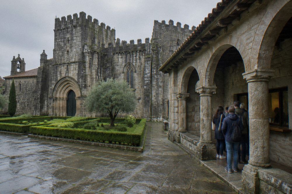 A ticket window in a stone cloister with a wooden counter and a small queue of visitors