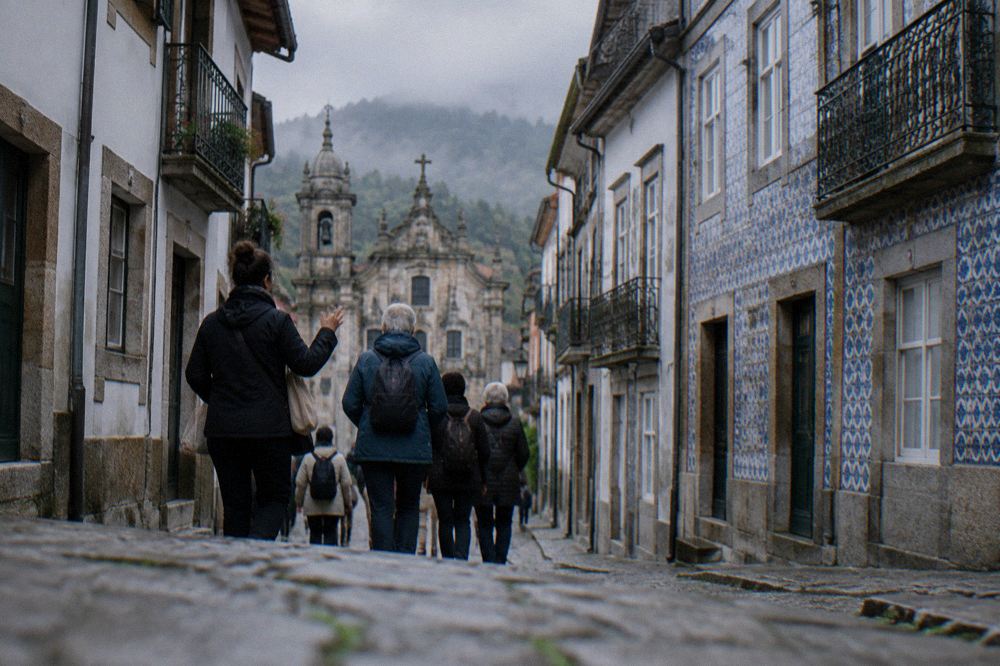 A guide leading a small group of visitors along a cobbled street of old buildings