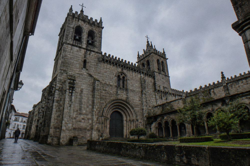 The Romanesque exterior and bell towers of Braga Cathedral seen from a narrow street in the historic centre