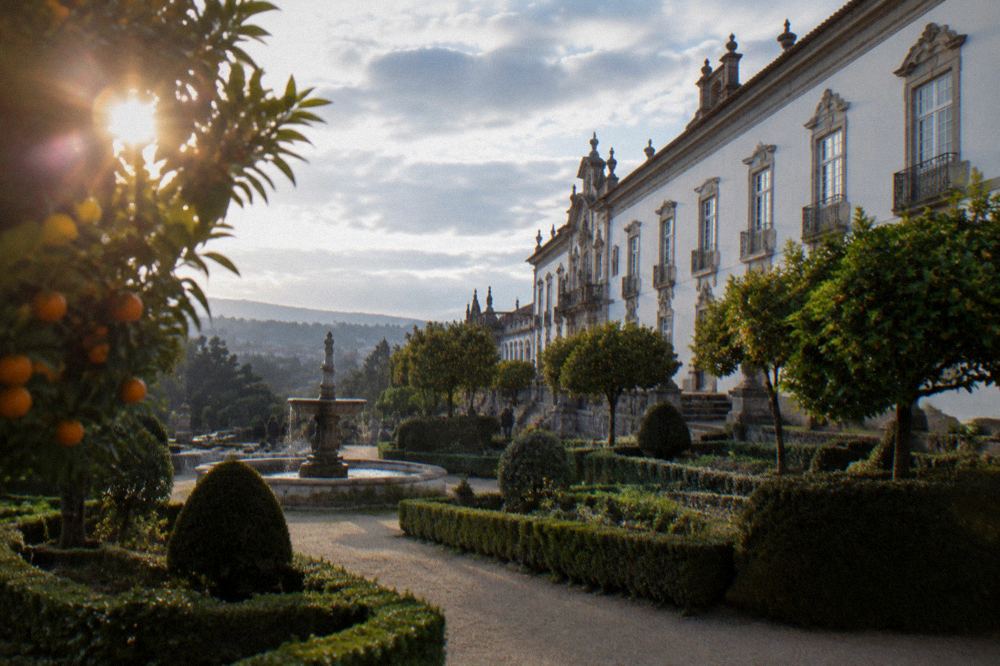 Formal garden with clipped hedges and orange trees beside a Portuguese palace museum