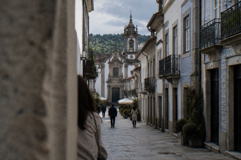 Narrow pedestrian street in Braga with old buildings and a church tower above