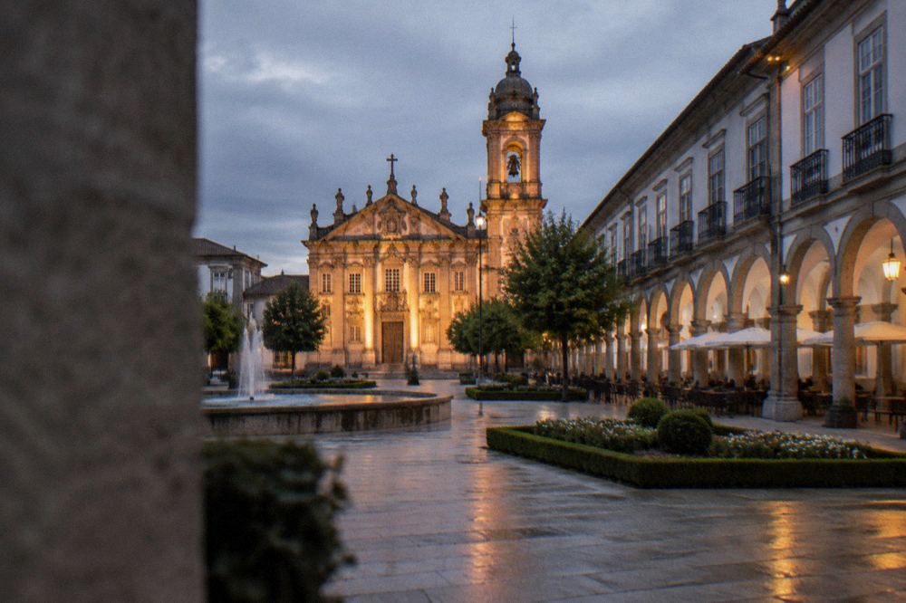 A floodlit baroque church façade and bell tower seen from an empty street at night