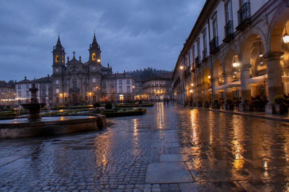 Wet cobblestone street reflecting streetlamp light after rain at night