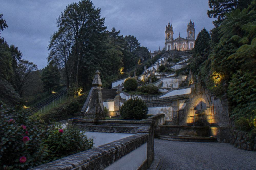 A monumental baroque stairway climbing a wooded hillside, lined with fountains and sculpted terraces