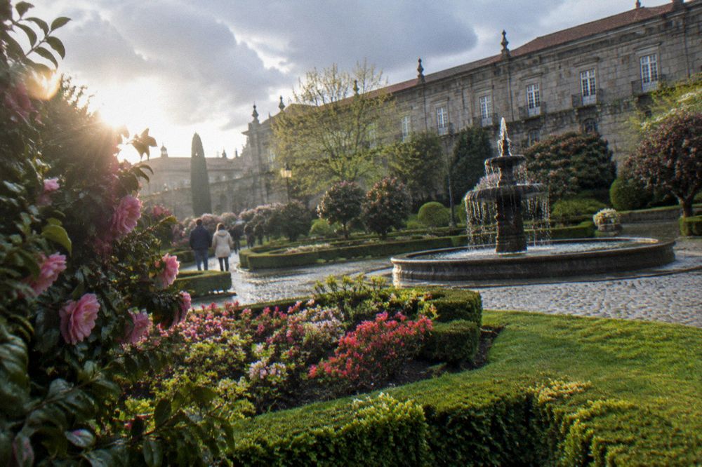Flowerbeds in full spring bloom in a city garden, with wet cobbles and a fountain