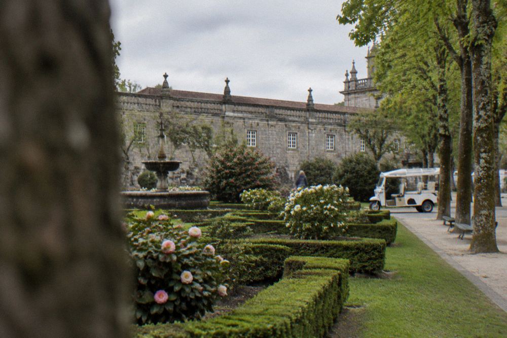 A small open electric tuk tuk vehicle parked on a tree-lined city square