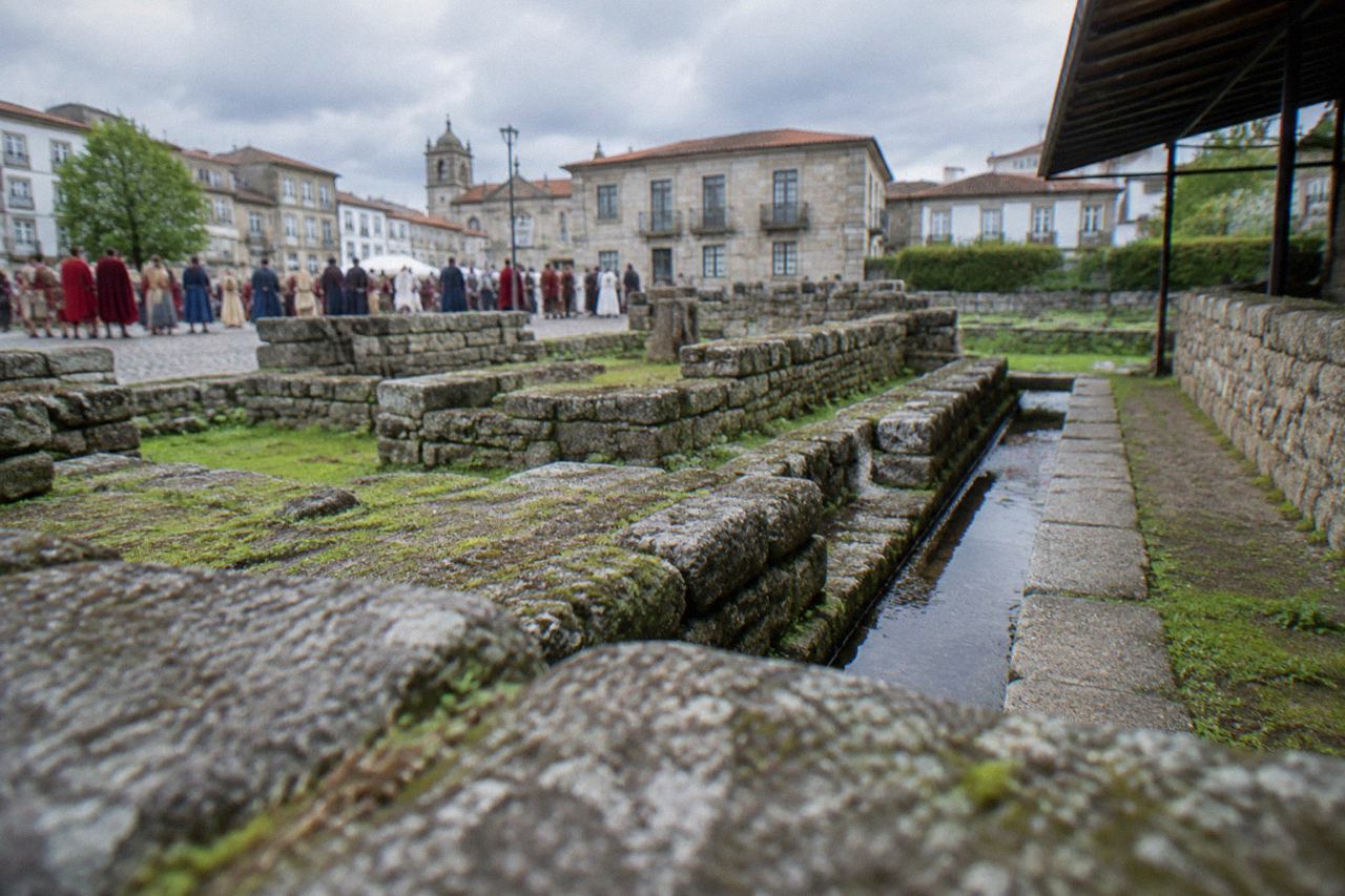 Crowds in costume gathered on a stone plaza in a Portuguese city during a historical festival