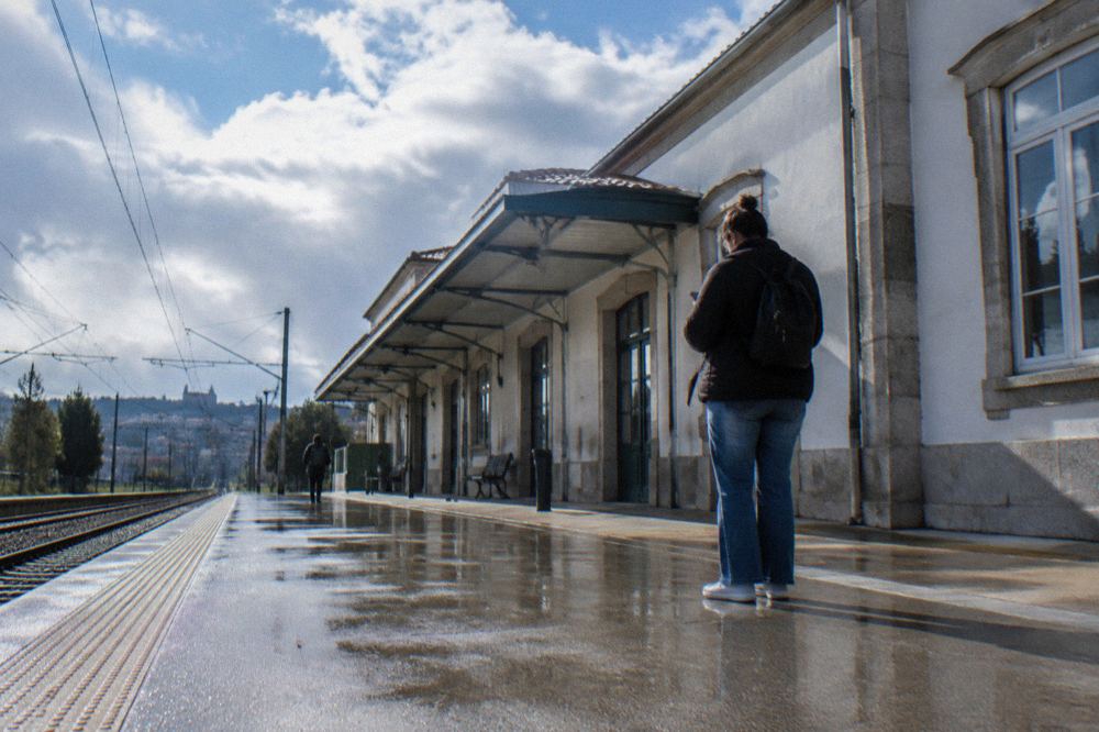 A passenger checking the departure board in a Portuguese railway station concourse