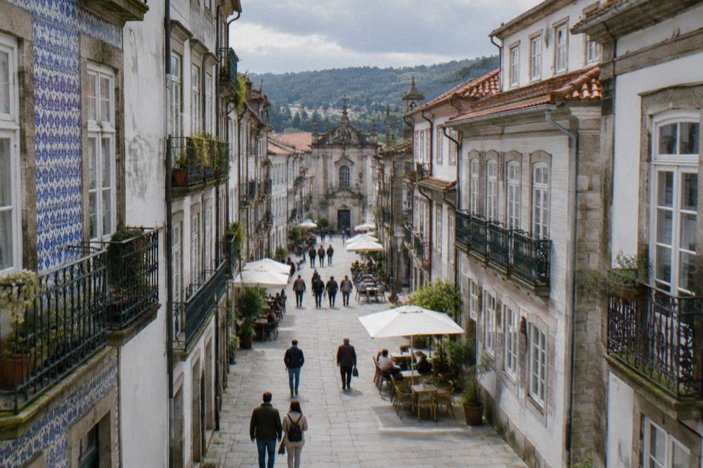 Visitors walking along a pedestrian street with café tables in a Portuguese historic centre