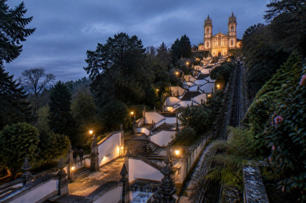 The illuminated stairway and sanctuary of Bom Jesus do Monte lit up against a dark evening sky
