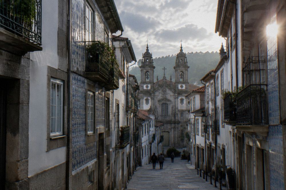 A narrow Braga street with baroque church towers rising above the rooftops in morning light