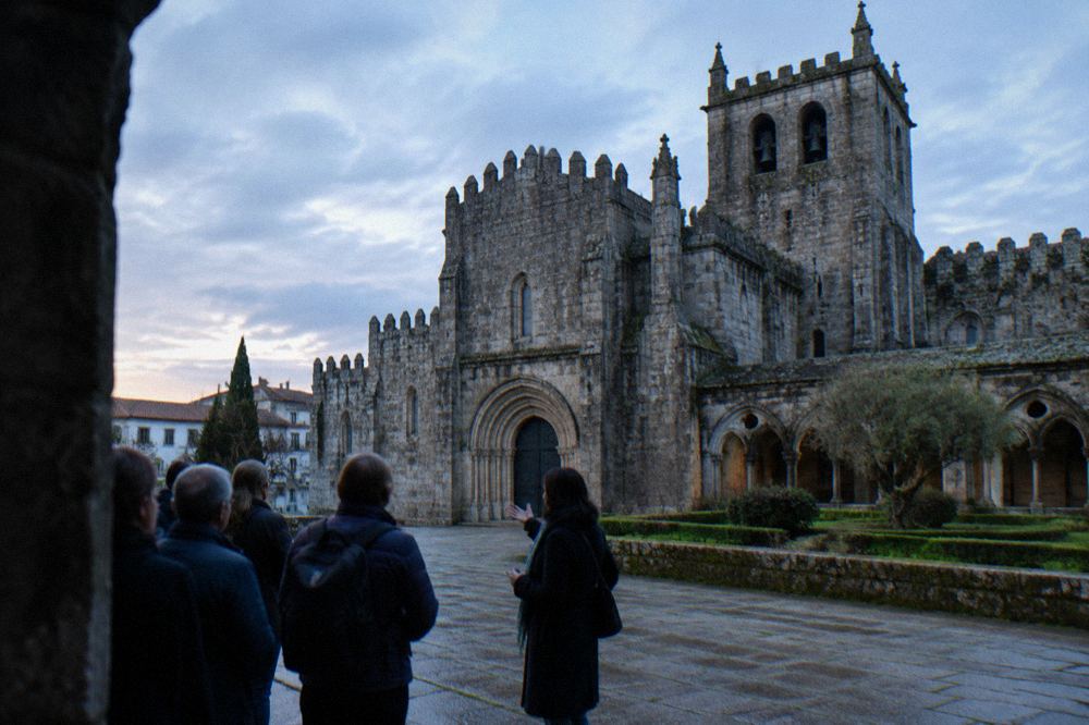 A guide speaking to a small group of visitors beside the Sé de Braga cathedral