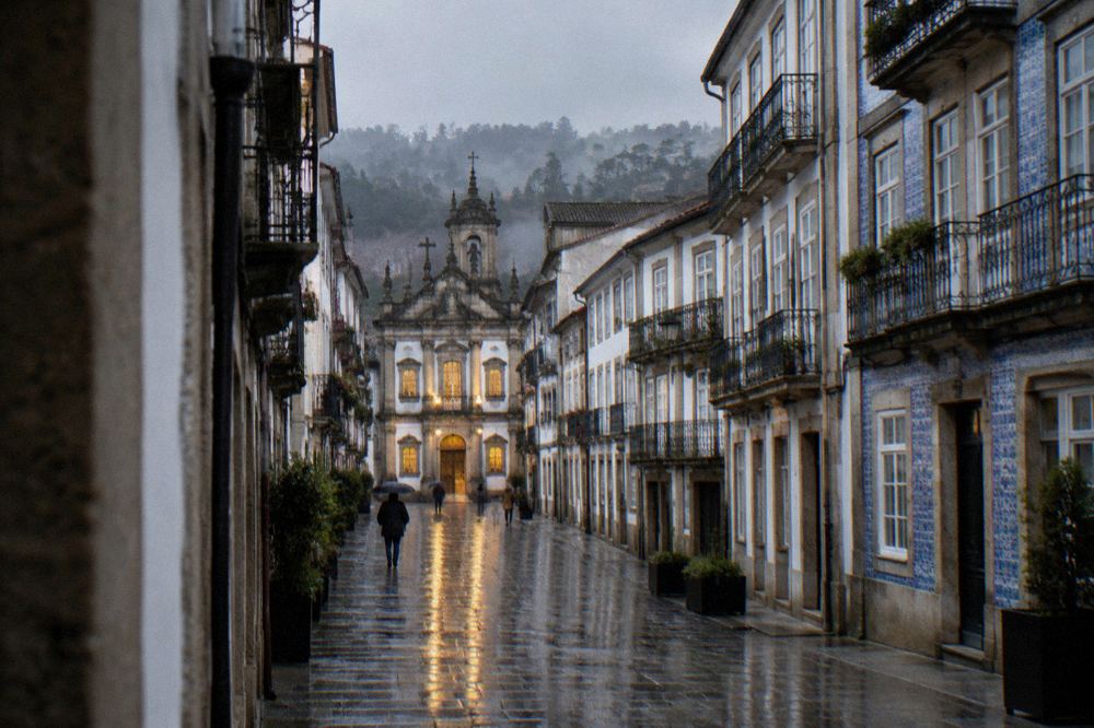 Rain-wet granite streets in Braga reflecting the lights of a baroque church facade