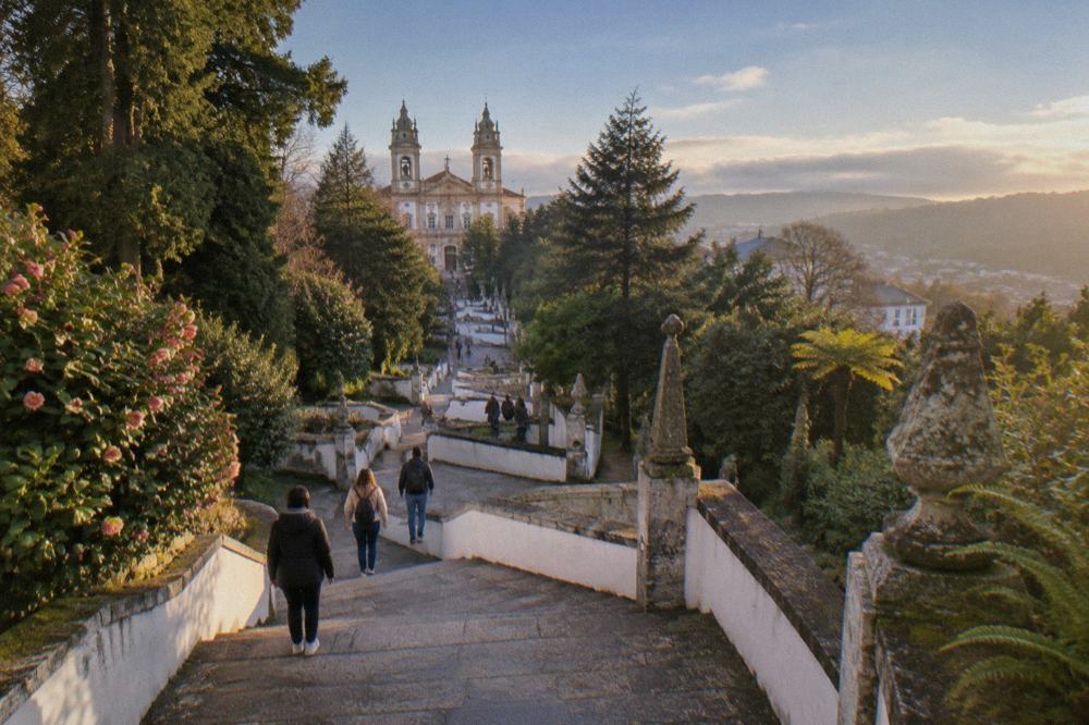 Visitors walking up the monumental baroque stairway at Bom Jesus do Monte under a clear blue sky