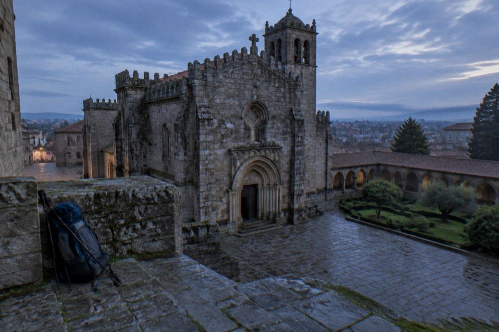 A pilgrim's backpack with walking poles resting against a stone wall