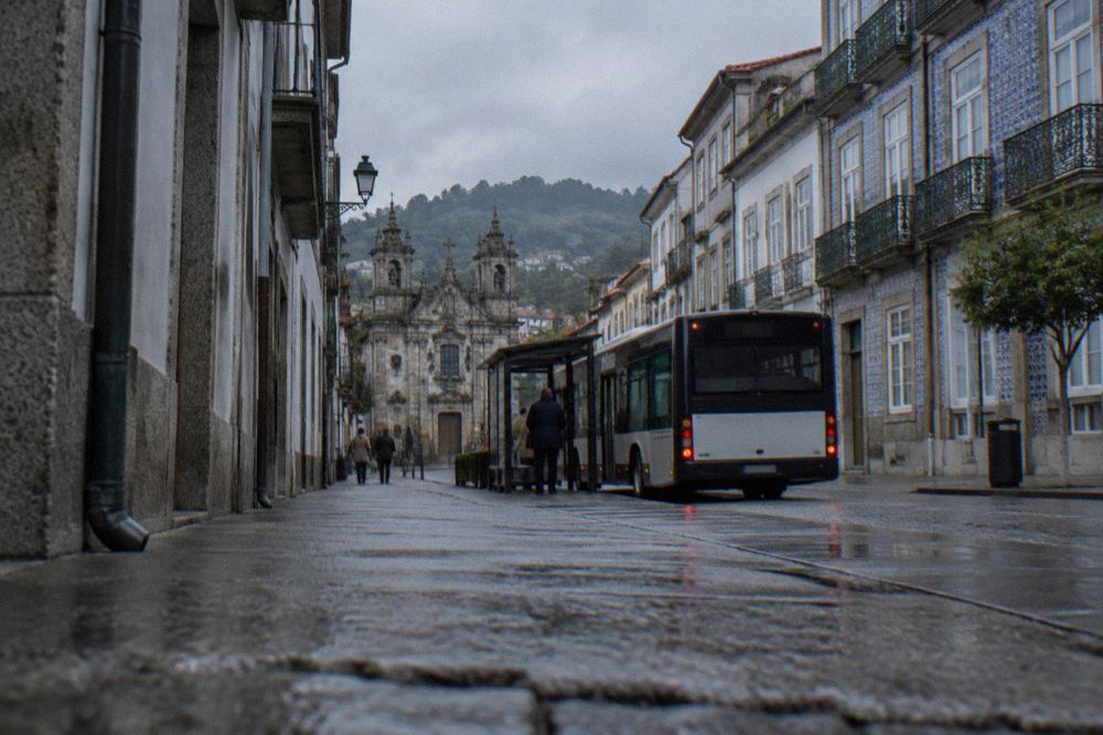 A city bus stopping at a kerbside shelter on a street in Braga