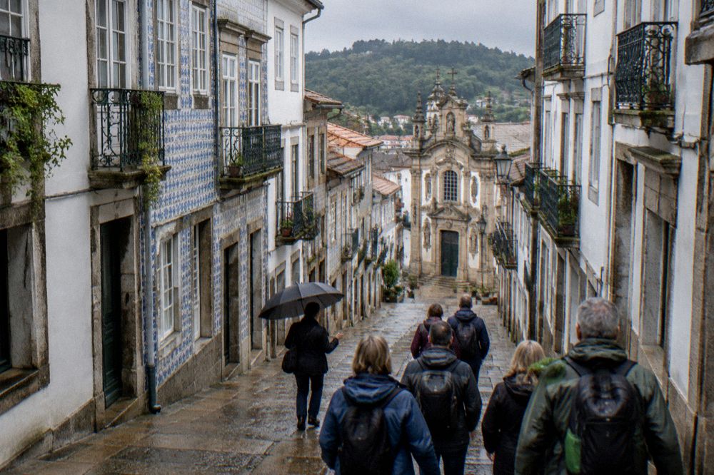 A guide with an umbrella leading a group of visitors through a narrow street in Braga