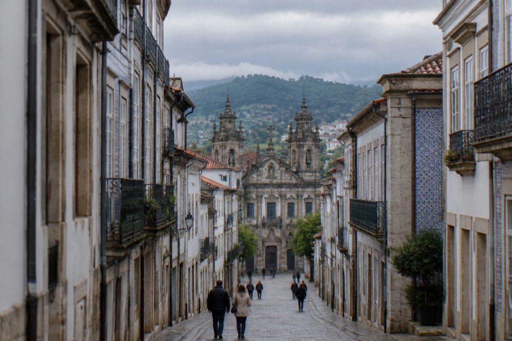 A stone cross on a grassy summit overlooking the rooftops of Braga at golden hour