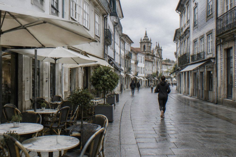 A café terrace with small marble tables on a pedestrian street in a Portuguese city centre