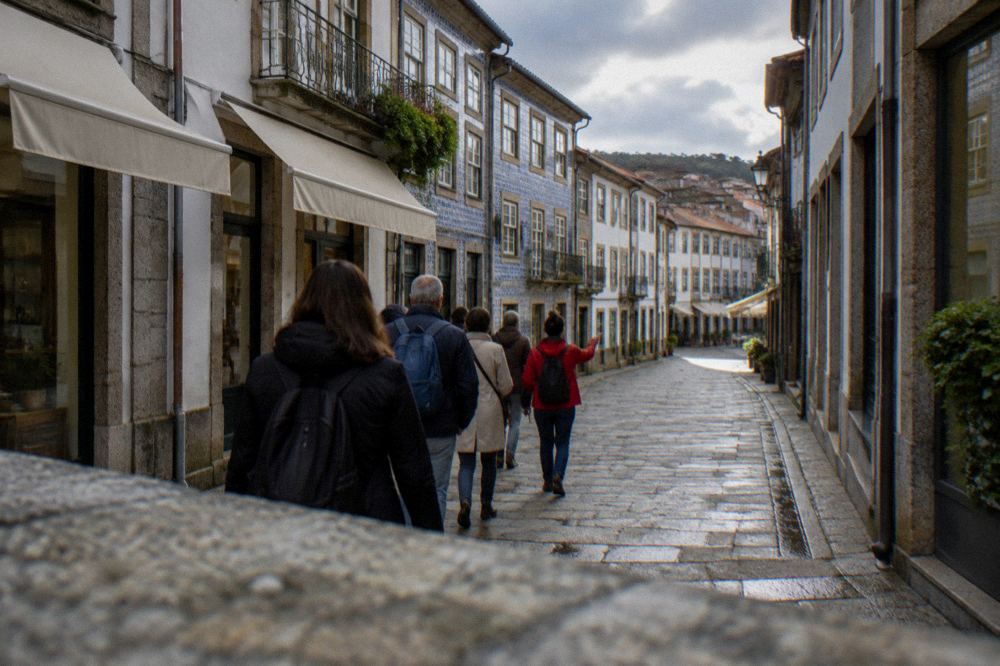 A small group of visitors following a guide along a narrow street of old buildings