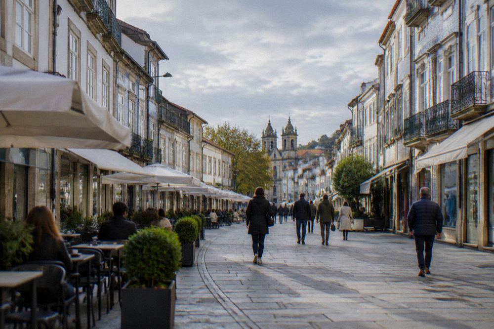 People strolling along a pedestrian shopping street in Braga lined with café tables
