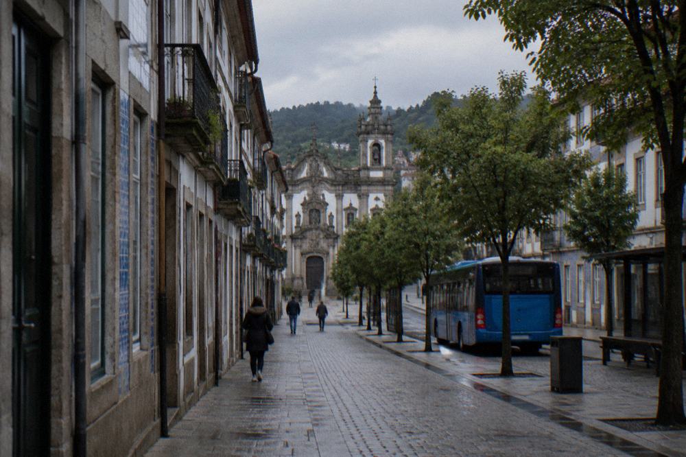 Blue city bus parked at a stop on a tree-lined avenue in Braga