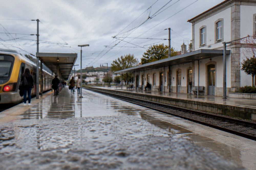 A small city railway station platform with a train at rest and passengers waiting