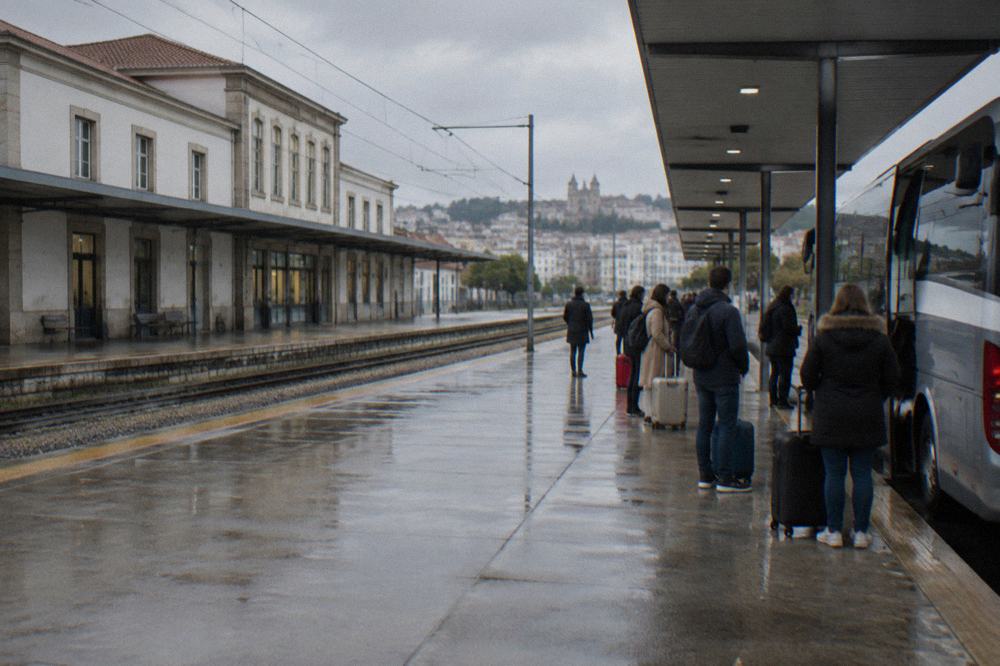 A regional coach parked at Braga bus station with passengers waiting with luggage at the platforms