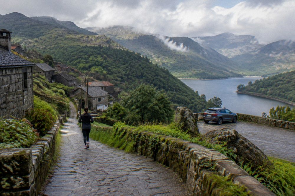 A car parked at a viewpoint above a reservoir in the Peneda-Gerês national park with forested mountains behind