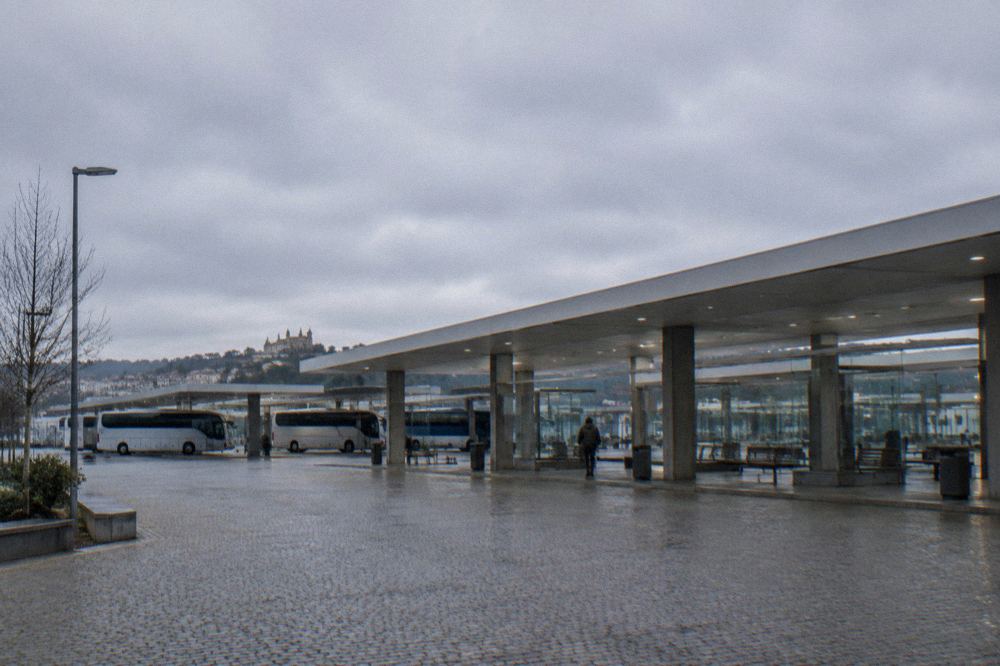 A regional bus station concourse with parked buses and a departure board