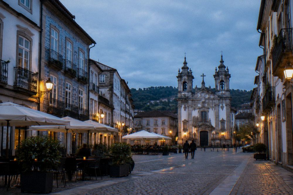 A cobbled square in Braga with baroque buildings and cafés under evening light