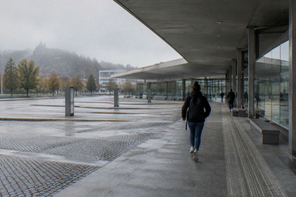 A traveller with a backpack looking at a departure board inside a bright bus station