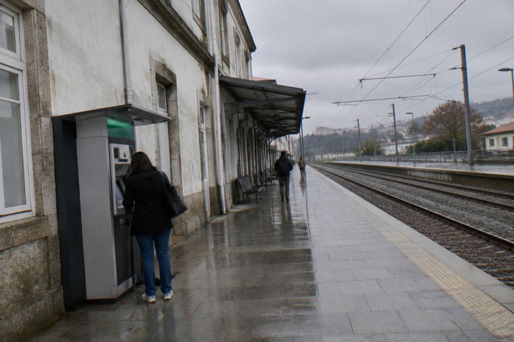 A passenger buying a train ticket at a CP ticket machine in a Portuguese station