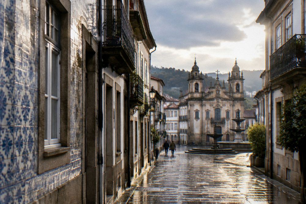 Sunlit baroque buildings and a fountain in a Braga square on a clear day