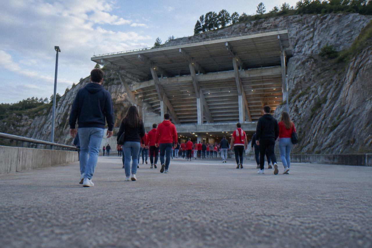 Football fans walking toward a modern stadium entrance on a sunny afternoon in Braga