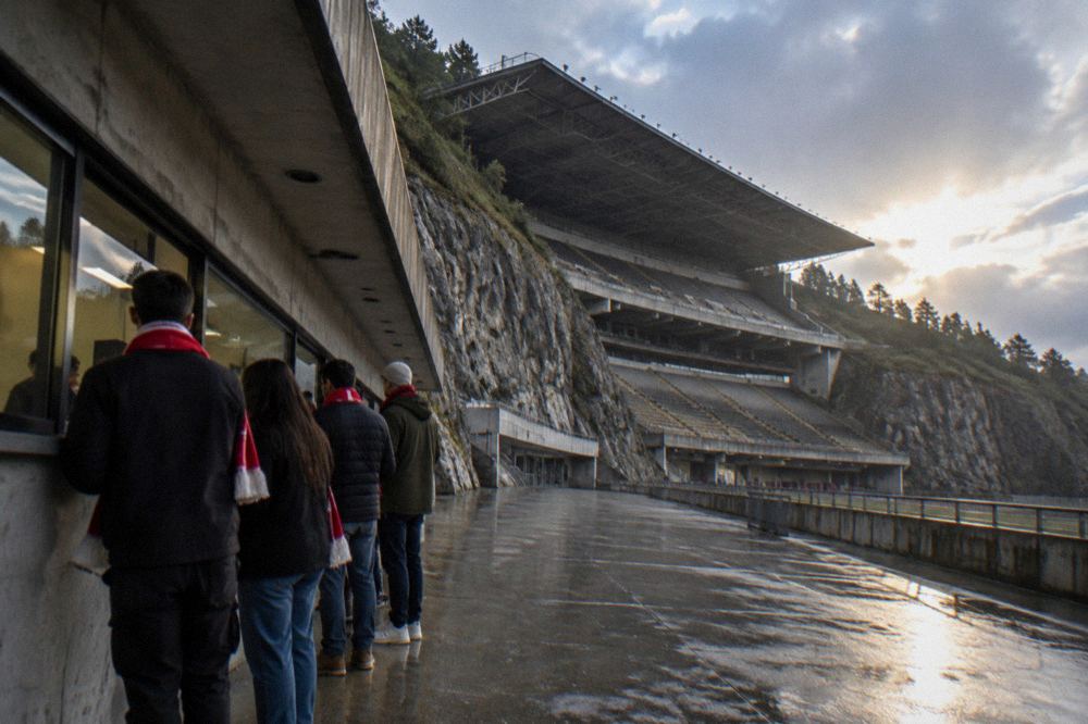 Supporters in red scarves buying tickets at a stadium window before a match